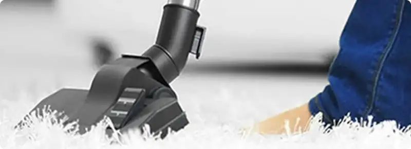 Close-up of a professional vacuuming a white carpet in Cataula.
